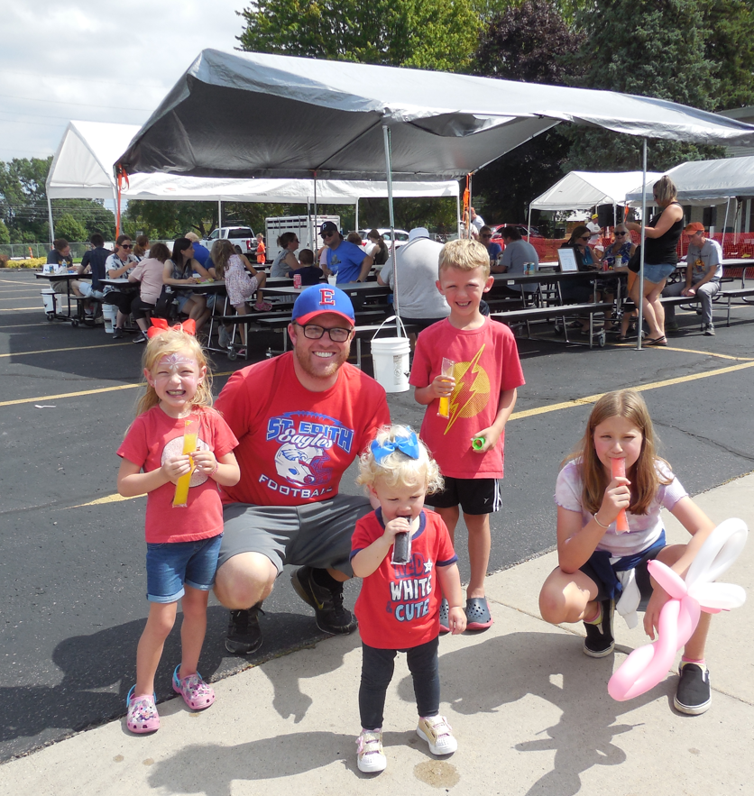 A man with four young children wearing matching red shirts at the 2022 St. Edith Picnic 